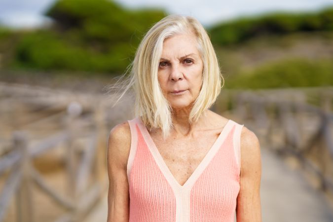 Portrait of mature female with grey hair on wooden walkway near the coast