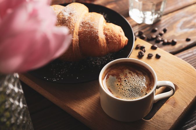 Croissant on plate on wooden table with coffee