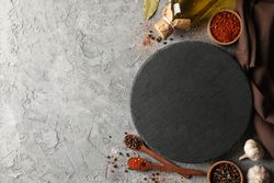 Composition with spices and round cutting board on gray background, space for text