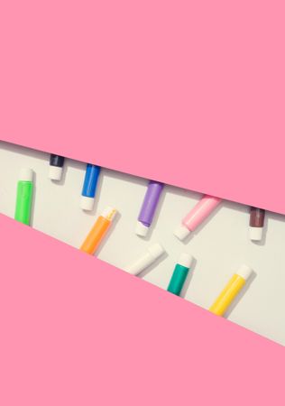 Pink paper with light geometric cut out and paint tubes