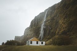 Rural house at foot of huge mossy cliff