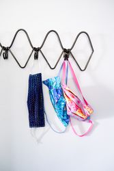 Front view of three colorful cotton coronavirus masks hanging on home coat rack
