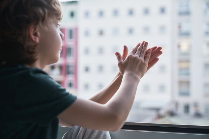 Boy staring out window and clapping hands