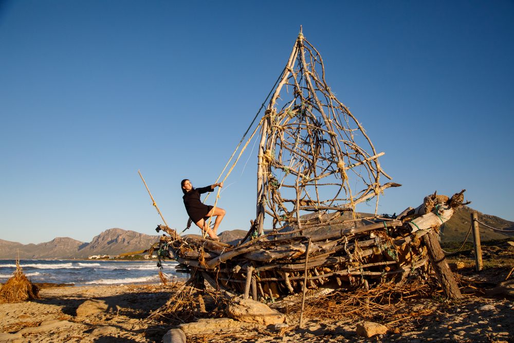 Young woman on decorative wooden ship near water on shore