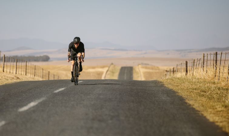 Male cyclist riding up a hill on road