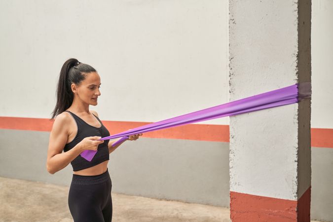 Sportswoman exercising with elastic band in gym