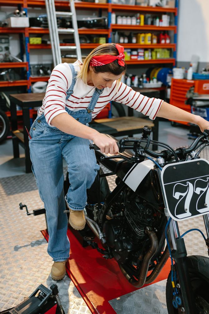 Mechanic woman starting custom motorcycle on factory