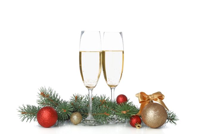 Champagne glasses, baubles and pine branches isolated on light background