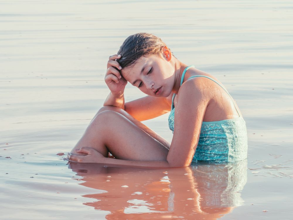 Teenage girl sitting in fresh water in sunny day