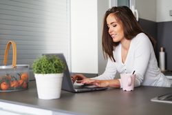 Smiling woman browsing on laptop and sitting on settee