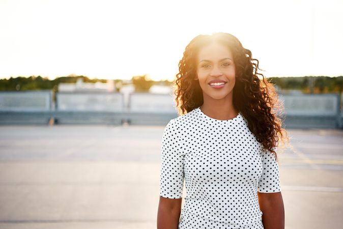Relaxed content Black woman on roof top with sun setting behind her