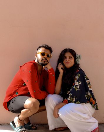 Man and woman crouching beside wall