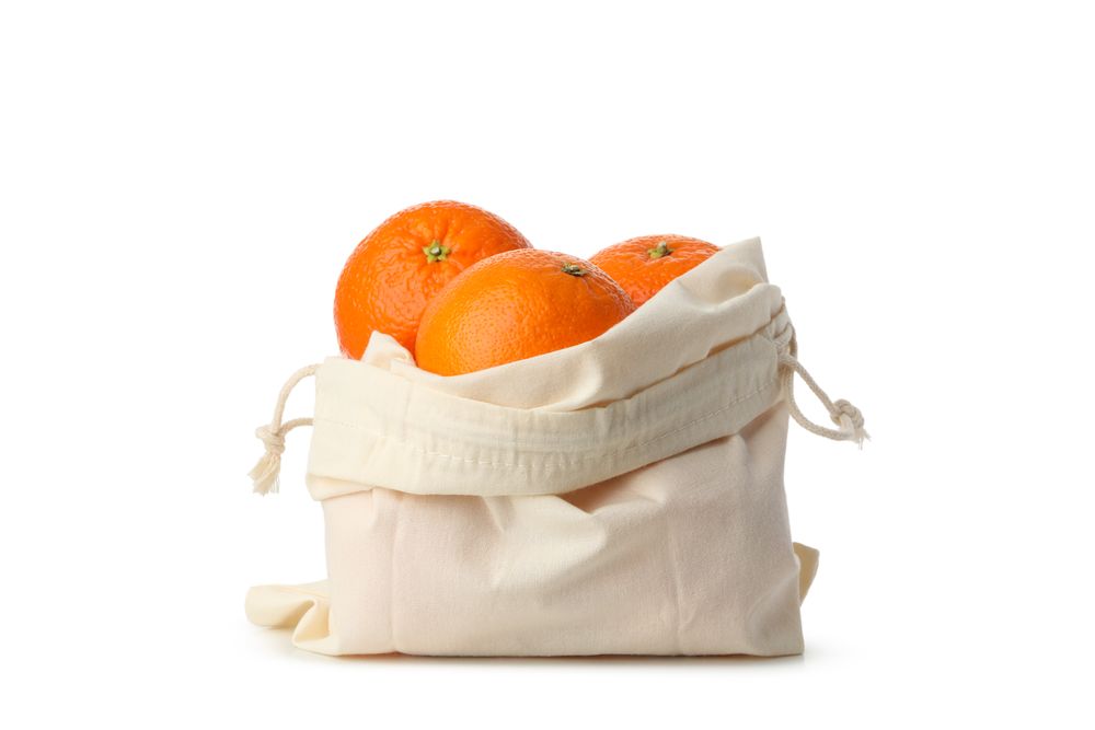 Cotton bag with ripe mandarins isolated on light background