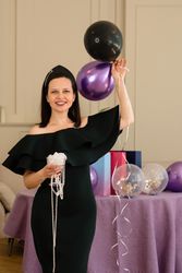 Woman holding balloons and jewelry, smiling at birthday party.