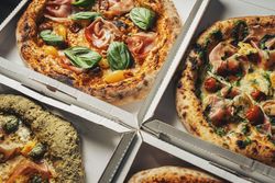 Gourmet artisan pizzas with fresh toppings in delivery boxes close-up