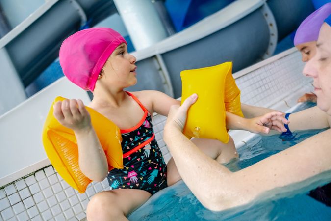 Mother putting water wings on girl