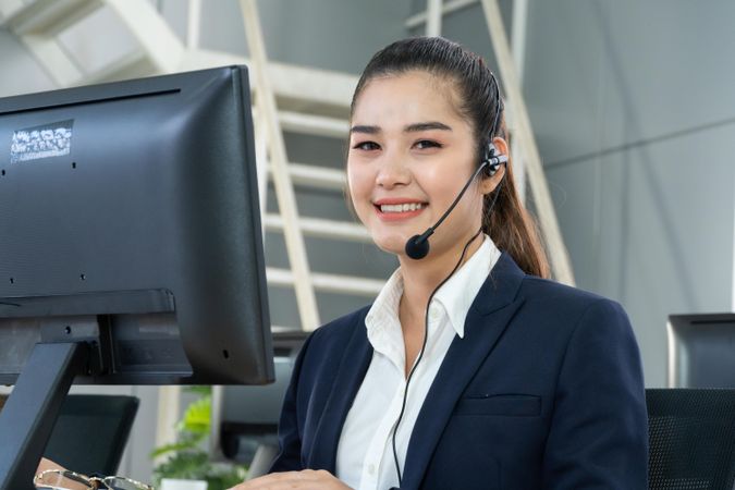 Smiling female speaking on headphones in call center