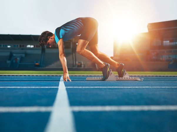 Male athlete on starting position at athletics running track