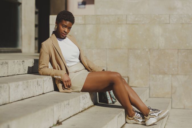 Stylish Black woman sitting on steps on street