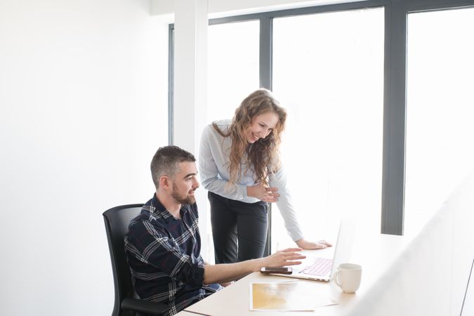 Cheerful colleagues working on laptop together