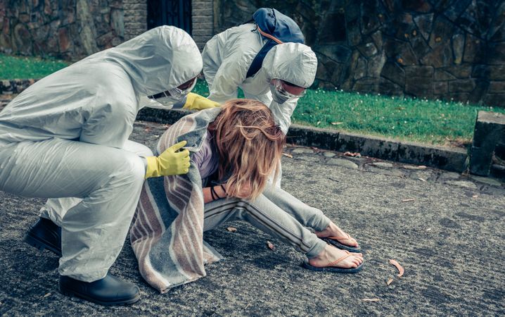 Doctors in protection suits caring for a woman