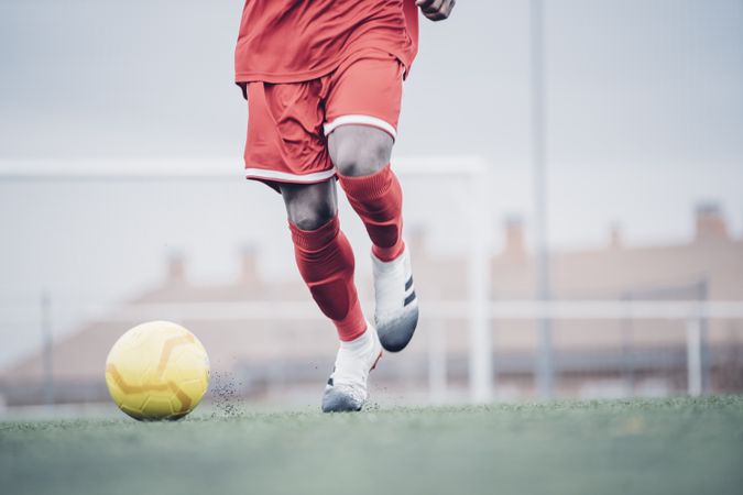 Black soccer player with red outfit playing soccer.