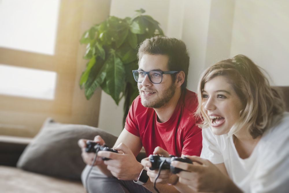 Couple with gamepads playing console
