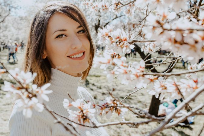 Young happy woman between trees in garden