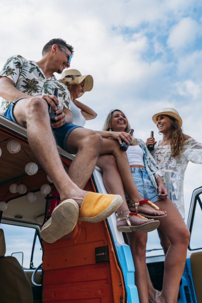 Relaxed friends comfortable placing on top of blue car