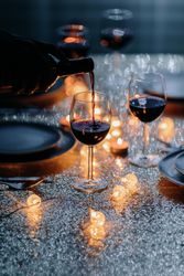 A hand is shown holding a wine bottle pouring into a wine glass