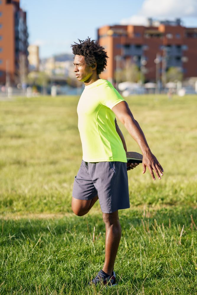 Man stretching legs behind him at park