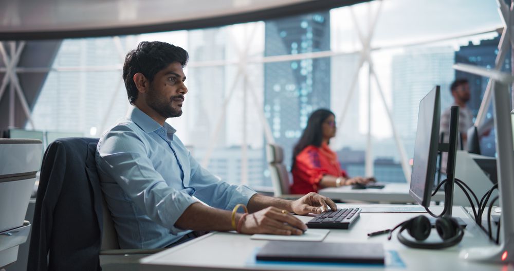 Portrait of an Indian Businessman Working on a Desktop Computer in a Fintech Startup Company.