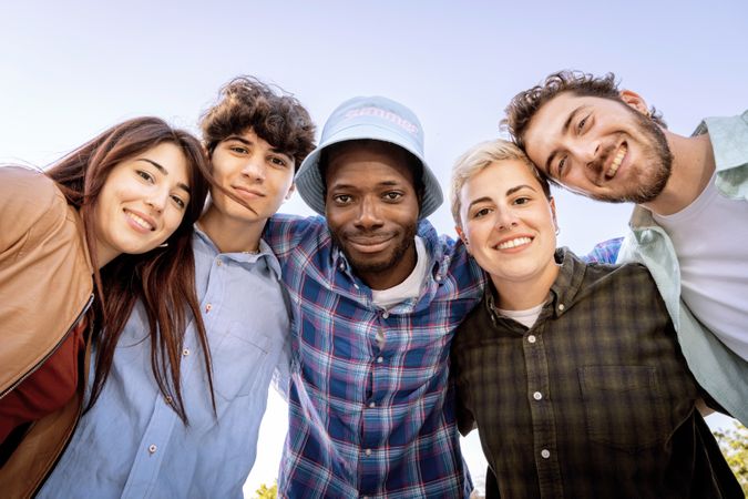 Happy group of young multiracial friends smiling and looking at camera outdoors