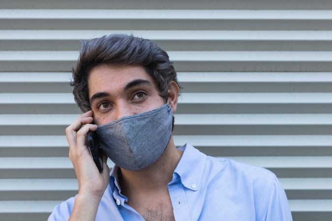 Man in mask talking smartphone on street