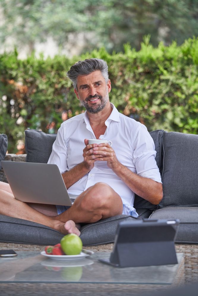 Mature businessman with netbook drinking coffee outside