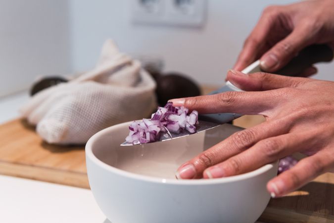 Crop woman cutting onion in kitchen