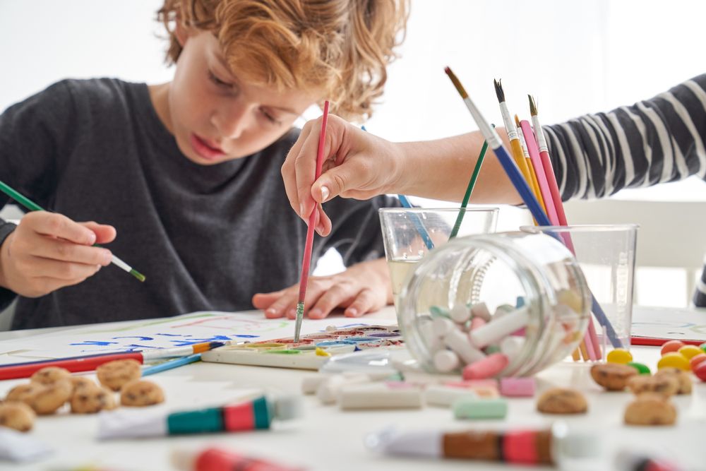 Boy painting near faceless friend
