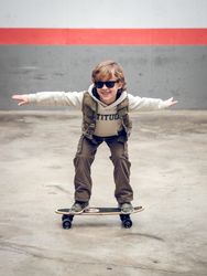 Stylish child riding skateboard on street
