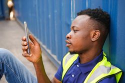 Man in high visibility vest checking phone on site