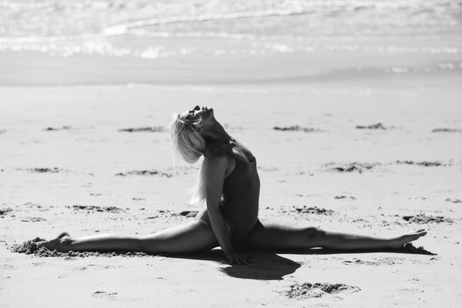 Woman doing splits on sand on a Spanish beach in b&w