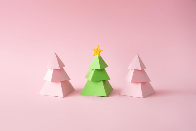Pink and green paper Christmas trees on pink background