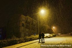 Silhouette of man and woman walking on the road during snowy night 5pZ1eb