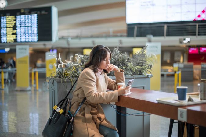 Woman sitting and using smartphone at airport