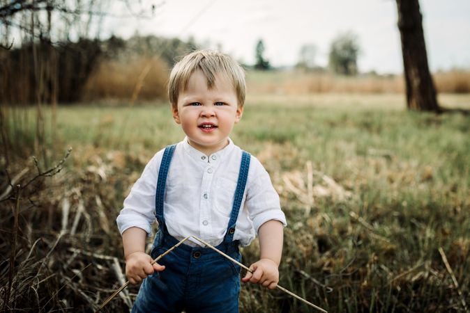 Portrait of boy in blue denim jeans standing on brown grass field