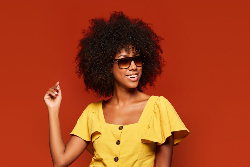 Bright woman with hands behind head smiling at camera