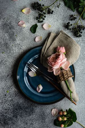 Delicate flowers on grey napkin and blue plate with silverware