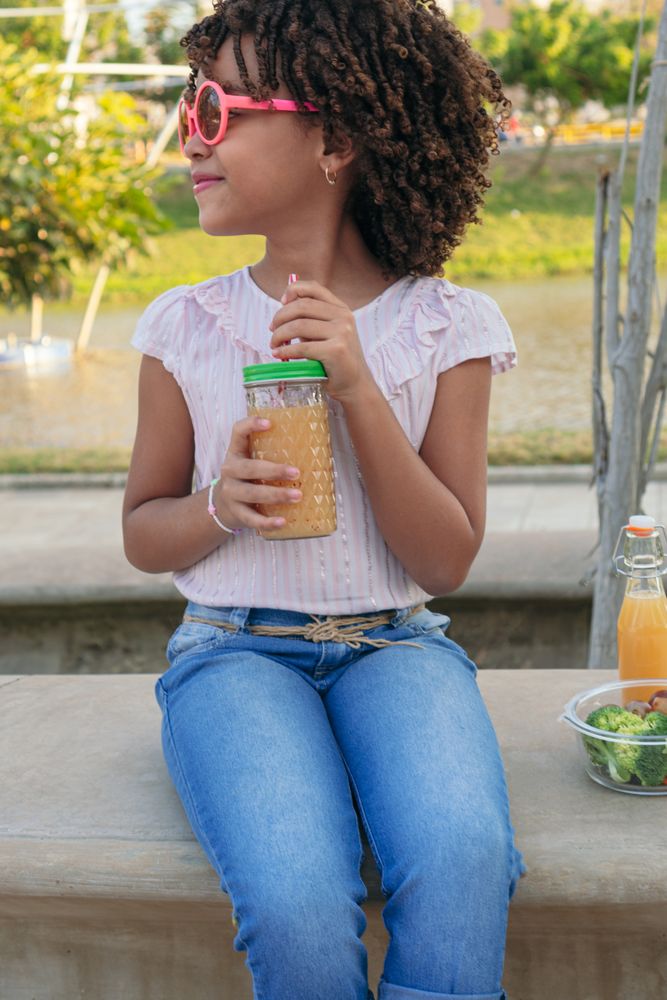Portrait of a girl in a park with a glass of healthy juice.