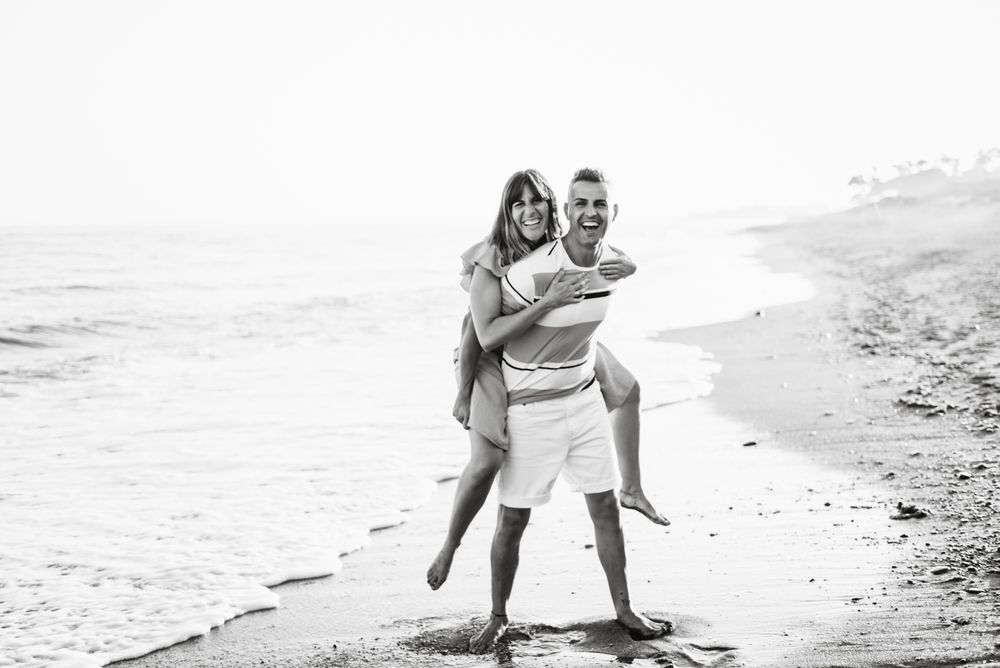 Man carrying woman on back near sea