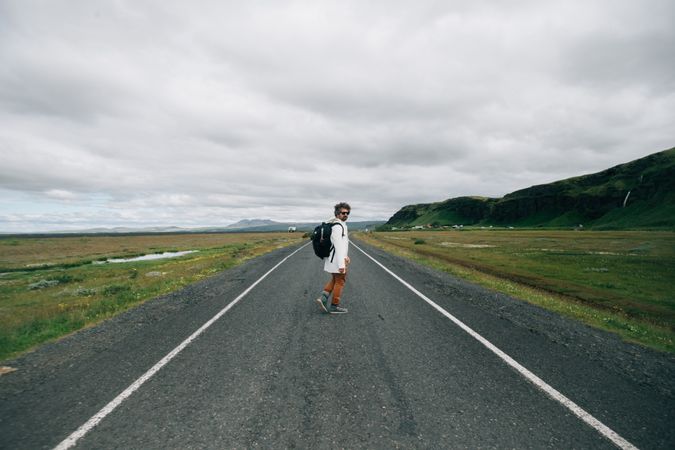 Man turns around while walking down desolate road