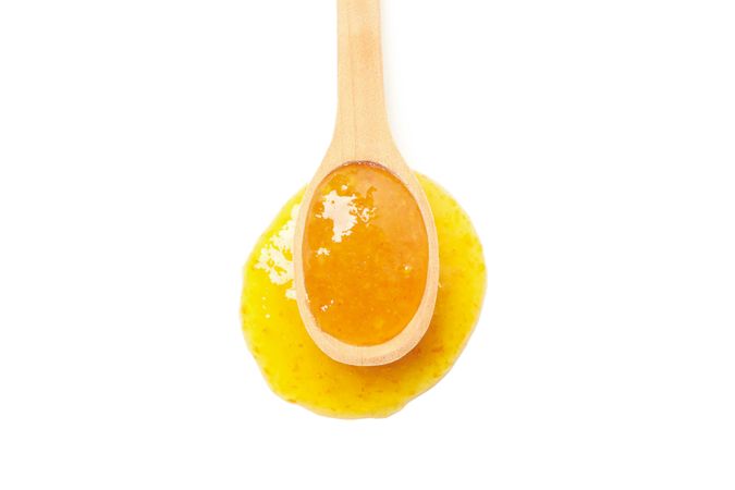 Wooden spoon with apricot jam isolated on plain background